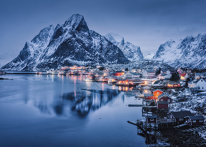 冬季景观村庄的房屋,城市的照明,雪山,大海,蓝色多云的天空黄昏时反射水中晚上美丽的雷恩,洛芬岛,挪威挪威罗布尔图片
