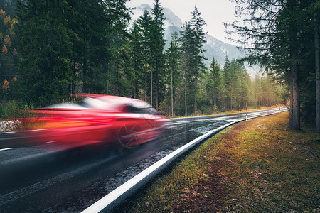 模糊的红色汽车秋天的森林里的道路上运动阴雨天完美的沥青山路巷道,意大利阿尔卑斯山的松树运输雾林中的公路图片