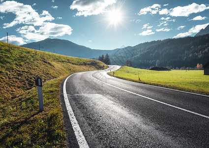 意大利白云石山谷中阳光明媚的早晨的道路风景与沥青道路,草地与绿草,山,蓝天与云太阳田野的公路欧洲旅行旅行图片