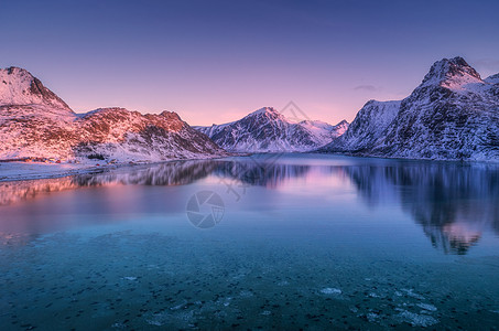 湖雪黄昏时,雪覆盖的山脉五颜六色的天空反射水中冬天的景观大海,雪岩,紫色的天空,日落时的倒影洛芬岛,挪威黄昏自然背景