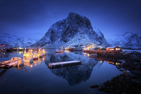 晚上船的渔村,洛芬岛,挪威冬天的风景房子,码头,照明,雪山,大海,蓝色多云的天空黄昏时反射水中挪威罗布尔图片