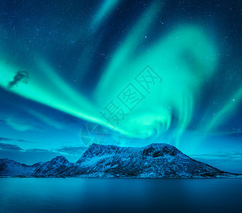 挪威洛福腾群岛雪山上方的北极光冬天的北极光夜间景观与绿色极地灯,雪岩,蓝色的海洋美丽的星空极光北极光白雪覆盖图片