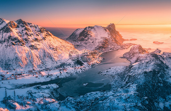 挪威洛福滕群岛日落时美丽峡湾的鸟瞰图冬天的风景雪山,蔚蓝的大海金色的阳光雪中岩石的顶部景观,村庄北部海岸线图片