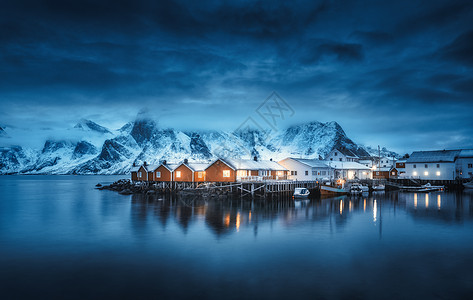 冬天的风景房子,照明,雪山,大海,蓝色多云的天空夜晚反射水中黄昏时船的小渔村,洛芬岛,挪威挪威罗布图片