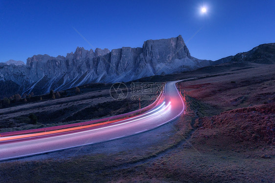秋天的夜晚,蜿蜒的道路上模糊的汽车前灯风景与沥青路,轻小径,山,蓝天与月光黄昏意大利的巷道月亮公路岩石上图片