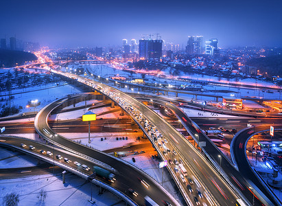雾中夜间俯瞰现代城市的道路公路交通的顶部视图冬季城市景观与高架道路,汽车,建筑,照明欧洲的立交桥高速公路图片