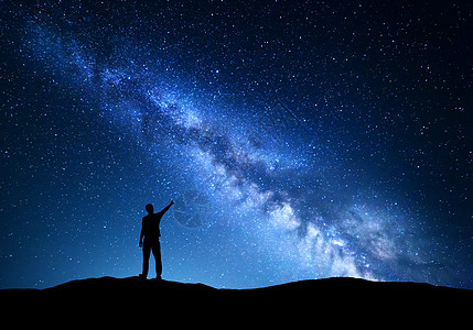 银河系个站着的人山上夜空中指指点点的剪影五彩缤纷的夜晚景观与美丽的宇宙旅行背景与蓝天充满星星惊人的银河图片