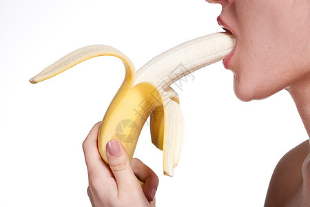轻的女人咬香蕉隔离白色图片