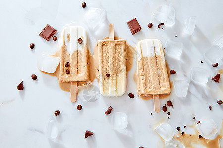 纯素香蕉咖啡奶油乳制品免费冰棒冰大理石背景与块巧克力咖啡豆,顶部视图自制的冷巧克力软糖冰棒冰大理石背景上与块巧图片