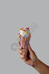 位女士的手着融化的香草冰淇淋,灰色背景个灰色背景的华夫饼锥里文本的个女人的手着个华夫饼锥,图片