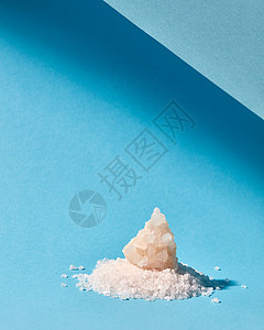 天然糖的晶体堆,用于烹饪装饰蛋糕张带的淡色蓝纸上甜糖堆大水晶装饰蛋糕隔离蓝色背景阴影上背景图片