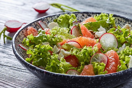 自制新鲜素食沙拉,灰色背景的盘子里放天然机蔬菜水果山羊奶酪健康饮食的美味的沙拉与天然成分生菜,萝卜片,葡萄汁图片