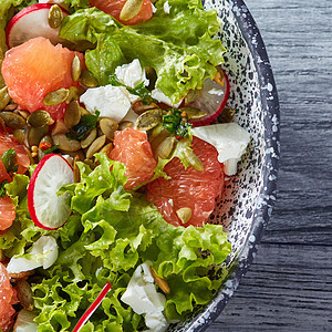 自制新鲜沙拉,绿色植物,萝卜,葡萄柚,奶酪,南瓜籽个灰色的盘子里,健康素食的顶级景观美味的天然沙拉图片