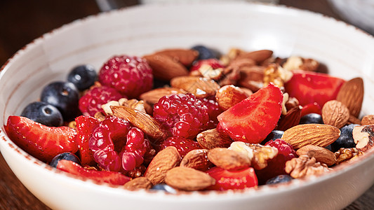 膳食天然早餐与新鲜机成分浆果,格兰诺拉,坚果个白色碗木制桌子上健康素食自制的麦片放碗里,草莓,杏仁,蓝莓,覆盆图片
