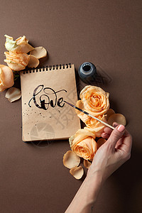 女孩用玫瑰棕色的背景上写了封祝贺的爱情用画笔写情书图片
