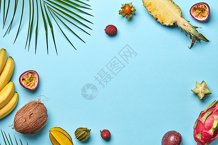 椰子,香蕉,杨桃,Physalis绿色棕榈叶蓝色背景与创造的食物框架平躺成熟同的异国水果图片