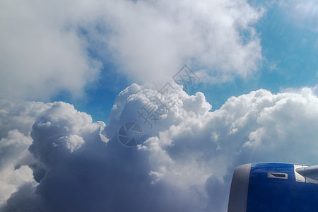 侧飞机发动机捕获时,飞机飞越天空飞机的机翼飞越蓝天多云的天空图片