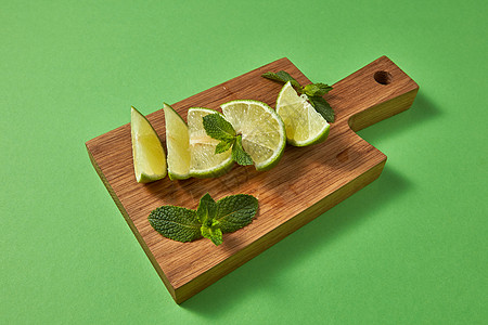 健康食品饮食理念多汁成熟的机绿色石灰片,绿色薄荷绿色背景上的木制切割板上新鲜的绿色石灰片绿色薄荷枝绿色图片