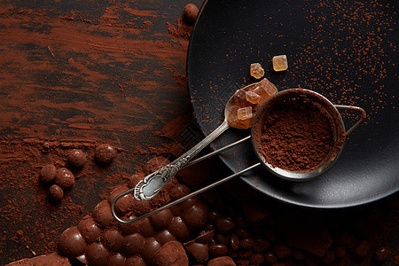 勺子与糖果可可粉个筛子上的黑色盘子,黑色背景与巧克力糖果可可粉图片