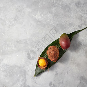 新鲜的芒果,整个椰子椰子壳与黄色冰淇淋棕榈叶上的灰色混凝土背景与大量的文本平躺套椰子,芒果冰淇淋球椰子壳上图片