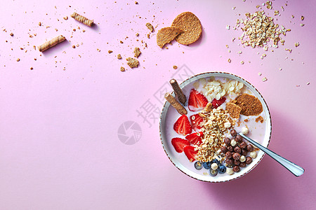 健康的冰沙白色碗与天然水果,燕麦片饼干的粉红色背景超级食物,自然排,饮食健康食品的风景碗白色的机酸奶图片