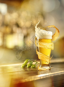 杯冷啤酒,溅周围,模糊的背景上,木背景上根啤酒花杯冷啤酒,溅水花,木制背景上跳背景图片