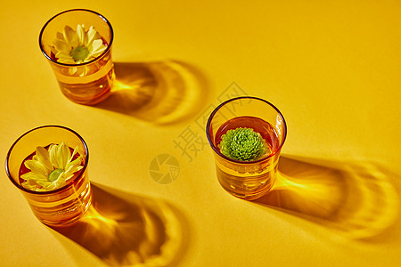 黄色透明眼镜,水黄色绿色的花个纸背景上,个图案阴影的风景三杯水花纸背景上,阴影图片