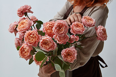 花瓶里芬芳的粉红色媒体玫瑰个轻的女孩着个花瓶花母亲节花店的着花瓶玫瑰的女孩背景图片
