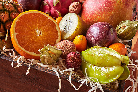木质背景上的盒子里多汁的新鲜热带水果西番莲,杨桃,荔枝,金橘,橙色半片,剑麻,特写盒子的特写,健康的新鲜水果图片