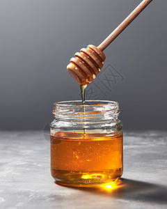 将机天然新鲜蜂蜜璃壶滴灰色厨房石材背景上,并犹太罗什哈沙纳假日芬芳的机新鲜蜂蜜木棒滴璃壶上的背景图片