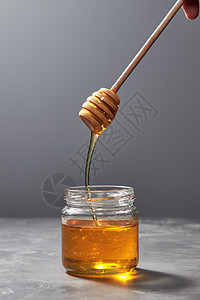 芬芳的天然机蜂蜜木棒滴入灰色的厨房桌子,放置文字下,纯天然的甜善犹太新健康假日甜花天然蜂蜜滴璃果酱与黄色透图片