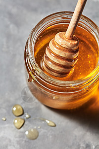 木棒放璃瓶里,灰色大理石桌子上放着芳香的天然机蜂蜜,放文字上罗什哈沙纳犹太新假期木制蜂蜜棒个璃锅背景图片