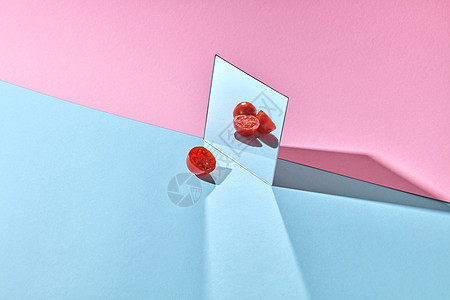 镜子,完整的减半的西红柿熟透的半蔬菜,背景双粉蓝色的纸,创意构图的番茄半镜子与西红柿个双背景图片