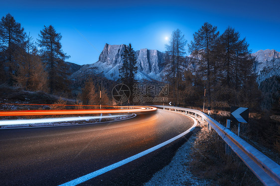 秋天的夜晚,蜿蜒的道路上模糊的汽车前灯风景与沥青道路,轻小径,山脉,树木,蓝天与月亮黄昏意大利的巷道看公路岩石图片