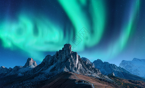 斯堪的纳维亚欧洲夜间山上的北极光北极光天空中北极光高岩石的星星美丽的景观与极光,建筑山上,山脊旅行背景