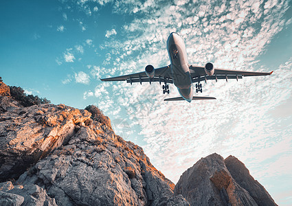大飞机夏天日落时飞过岩石景观与降落客机,山脉,彩色蓝天与云商务旅行商业飞机复古色调飞机图片