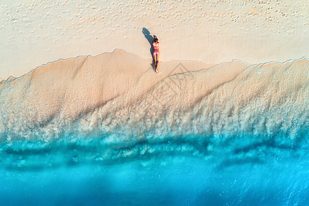 鸟瞰美丽的轻女人躺白色的沙滩上,靠近大海,日落时波浪暑假顶部的背运动苗条的女孩,清澈的蔚蓝的水感的图片