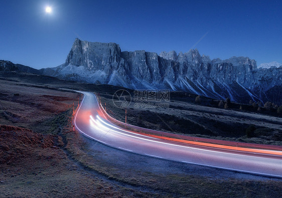 秋天的夜晚,蜿蜒的道路上模糊的汽车前灯风景与沥青路,轻小径,山,蓝天与月光黄昏意大利的巷道月亮公路岩石上图片