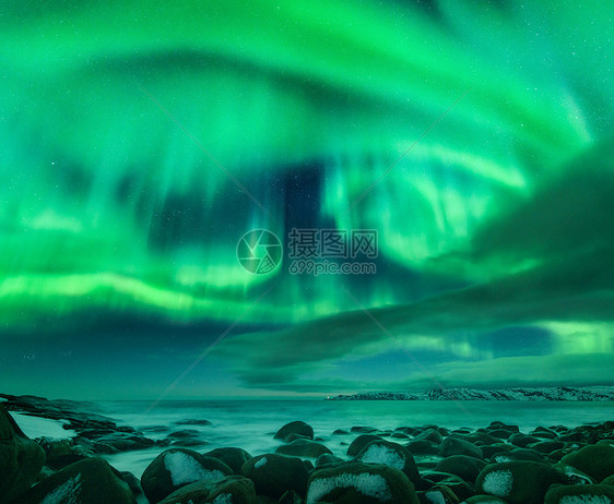 北极光海洋上俄罗斯泰伯卡的北极光星空与极地的灯光云彩夜冬季景观明亮的极光,大海里模糊的水中的雪石旅行图片