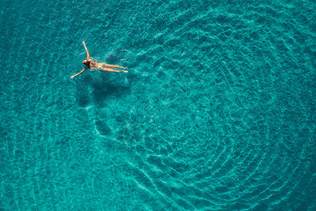 蓝色泻湖游泳女子的鸟瞰图土耳其奥卢德尼茨的地中海夏天的海景与女孩,清澈的蔚蓝的水,波浪阳光明媚的日子透明的水飞图片