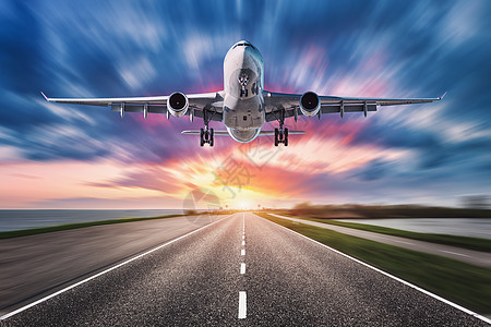 飞机道路日落时运动模糊效果旅客飞机的景观飞过沥青路五颜六色的天空商业飞机正降落背景模糊的飞机图片