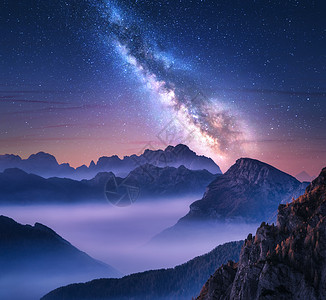 夏天的夜晚,银河雾中飞过群山景观与高山山谷,紫色低云,彩色星空与银河帕索Giau,白云石,意大利美丽的自图片