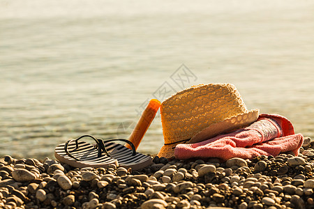 沙滩配件毛巾上进行日光浴阳光明媚的帽子拖鞋,石头石头沙子太阳帽拖鞋石滩上图片
