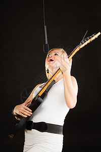 音乐,歌唱音乐天赋的女人电吉他上演奏,演播室唱歌,黑色背景女人弹电吉他唱歌图片