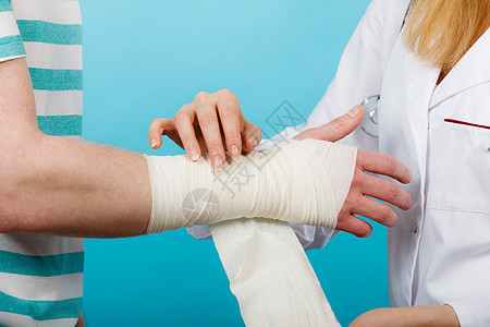 医学医疗保健女医生包扎男手扭伤手腕拜访医学专业人士的轻人医生包扎扭伤了手腕背景图片