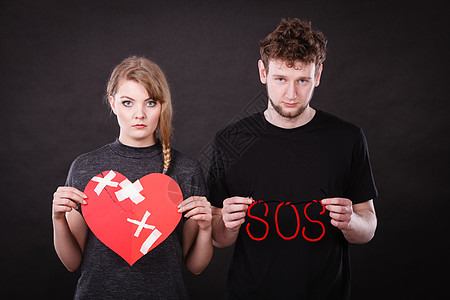背叛分手关系中轻的夫妇用大石膏破碎的心红色的SOS字符号符号负情绪心碎的轻夫妇SOS的话图片