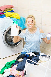 坐浴室里的轻女人把衣服整理成洗衣机深色衣服的女人着液体粉末洗涤剂女人洗衣服图片