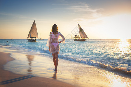 美丽的轻女人站大海里,沙滩上,日落时,帆船上,暑假旅行热带景观与苗条女孩穿着白色蕾丝连衣裙海滨,船只游艇图片