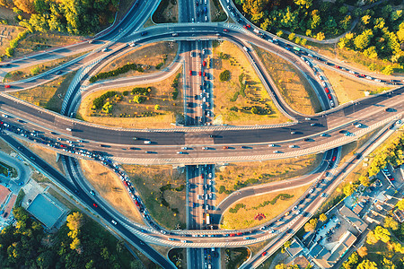 夏季日落时现代城市道路的鸟瞰图公路交叉口交通的顶部视图高架道路上汽车的景观,绿树立交桥繁忙的十字路口高峰时背景图片