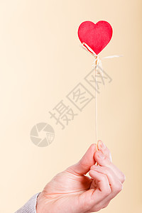 象征爱情浪漫的木棍上的心爱的象征由人的手臂支撑的杆上木棍上的心图片